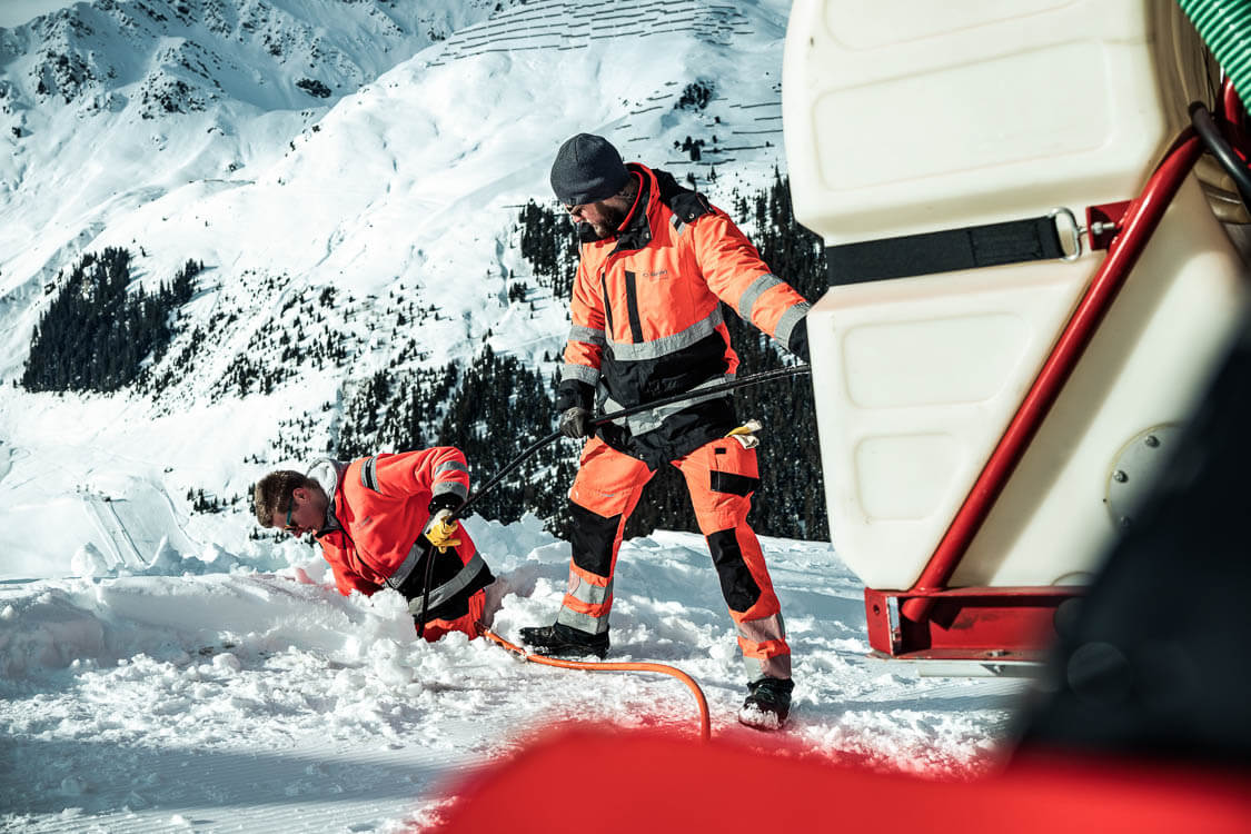 Zwei DAWI Mitarbeiter reinigen Kanal der Bergbahnen in exponierter Lage