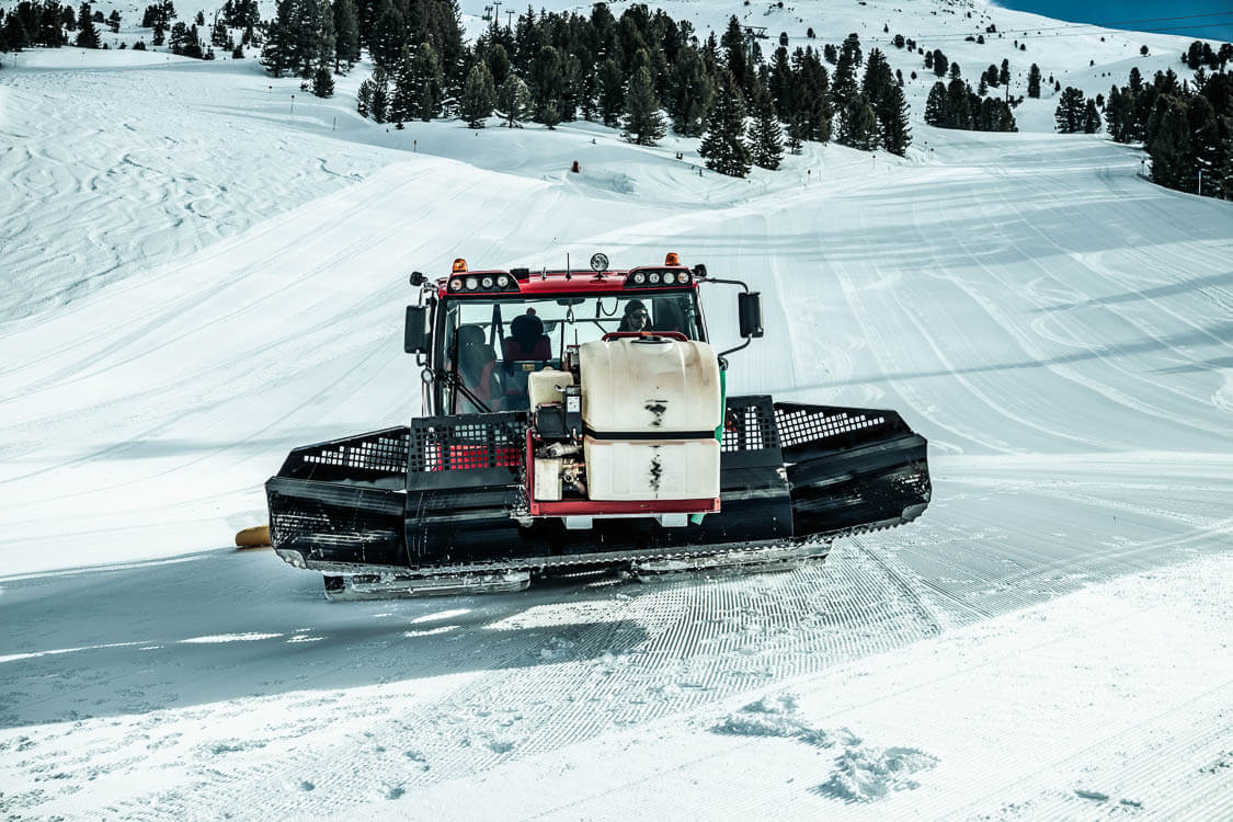 DAWI Mitarbeiter transportiert Gerätschaften für Kanalreinigung am Berg mit einer Pistenraupe